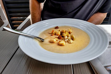 Thick garlic soup with roasted bread cube in white plate.