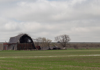 A dilapidated farm building on a flooded field.