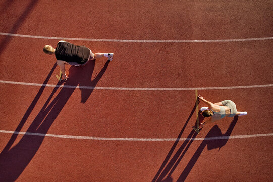 Two athletes in starting position on running track, aerial view