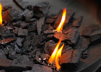 A pile of charcoal with a few pieces of wood burning