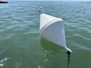 Floating white buoy in green seawater