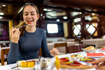 Young Woman Having Breakfast with Eggs, Bacon, and Vegetables