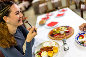 Young Woman Having Breakfast with Eggs, Bacon, and Vegetables