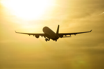 Take-off of wide body passenger airplane to the setting sun