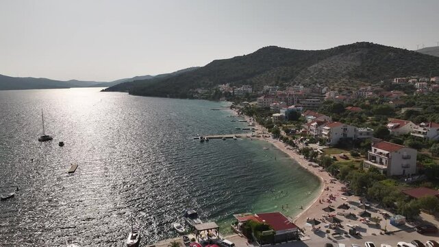 Aerial video shows wind-swept sea surface near Seget Vranjica as summer maestral blows, with boats bobbing in the bay and ripples crossing the calm Adriatic waters