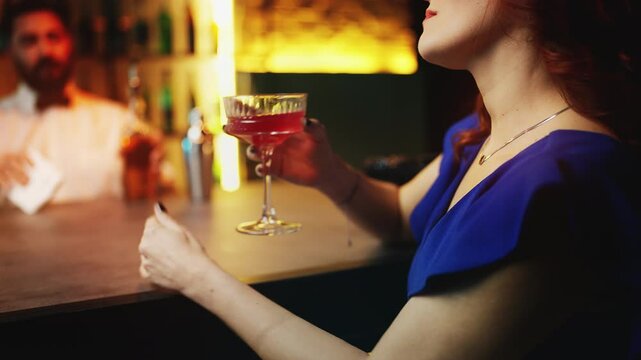 Young woman drinking cocktail at bar counter in pub, searching for a date