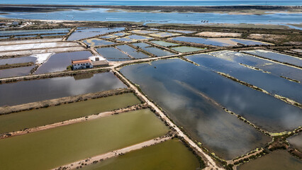 Luftaufnahme von Salinenbecken an der Küste mit Meer und Lagunen im Hintergrund