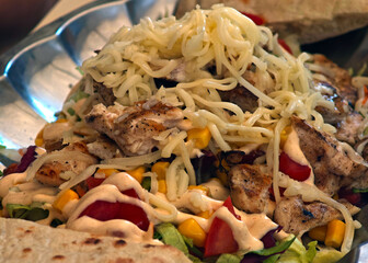 A plate of food with chicken, tomatoes, corn, and cheese