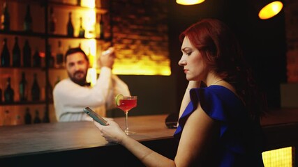 Lonely woman scrolling dating app on phone while sitting at bar counter