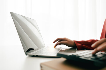 Accountant working at desk using calculator to calculate company's annual financial and tax report....