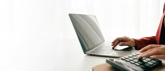 Accountant working at desk using calculator to calculate company's annual financial and tax report....