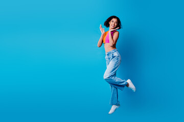 Young cheerful woman in stylish casual wear poses joyfully against a blue background in a vibrant...