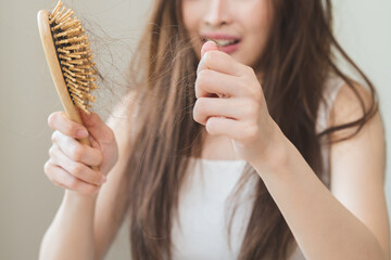 Damaged hair, amazed asian young woman, girl hand holding brush comb, hairbrush with fall hair from...