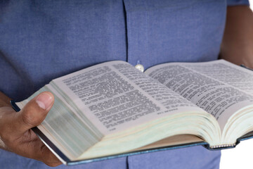 Fototapeta premium Man reading the Holy Bible, a moment of quiet study and worship. Concept of faith, spirituality, and prayer in Christianity. Close-up on open book pages and hands in contemplation.