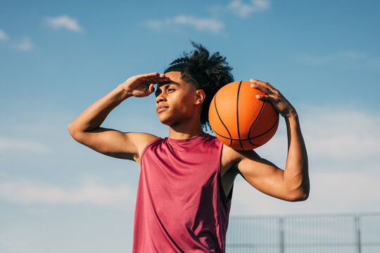 Young athlete holding basketball under blue sky