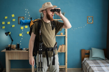 traveler using binoculars before hiking trip indoors