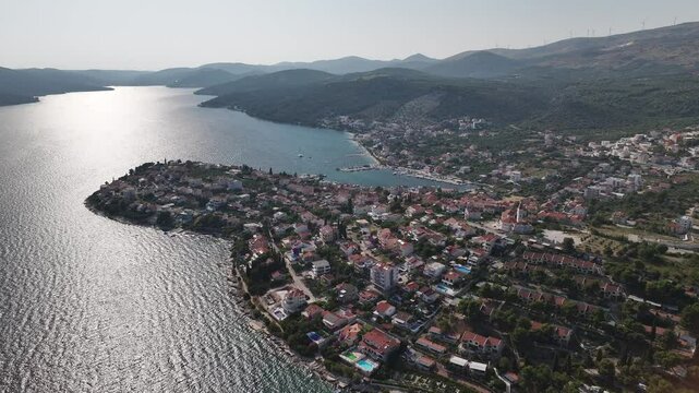 Aerial footage from across the bay shows Seget Vranjica from Trogir&rsquo;s perspective with houses, sea, and boats in a quiet coastal setting under warm skies