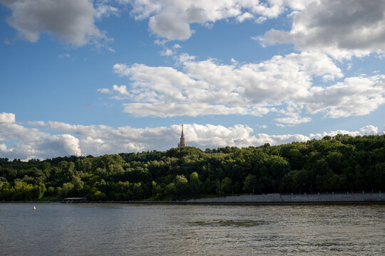 Scenic view of river embankment and green hill with main building of Moscow State University at sunny summer day