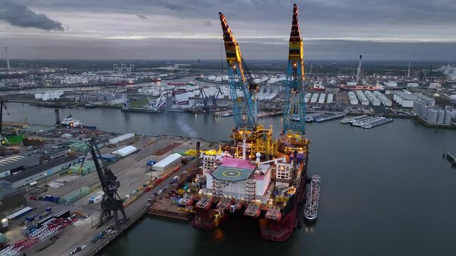 Rotterdam, Netherlands. Drone flight over industrial area with cargo ports, containers and a semi-submersible ship, heavy lifting crane. Machines designed for work at sea