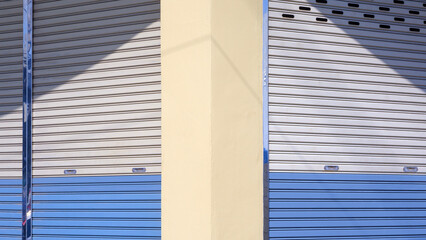 Front and side roller shutter doors of commercial building with light and shadow on surface, side view with copy space