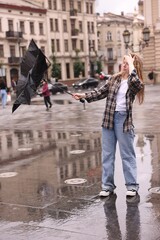 Woman with broken umbrella on city street