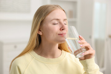 Young woman drinking water from glass at home