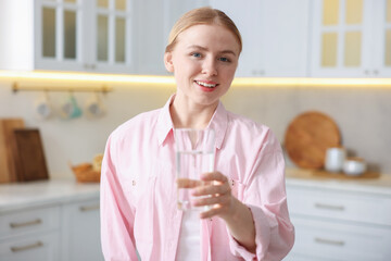 Young woman with glass of water in kitchen