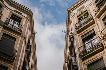 Narrow street in Gotic, Barcelona with tall old buildings and sky view