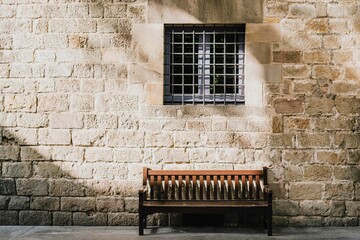 Wooden bench beneath historic stone wall with soft morning light
