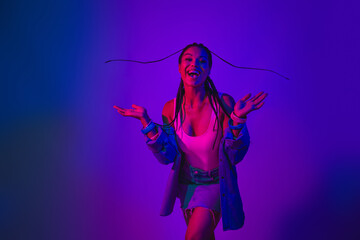 Fashionable young woman with a radiant smile in neon lighting celebrating in a joyful and trendy...
