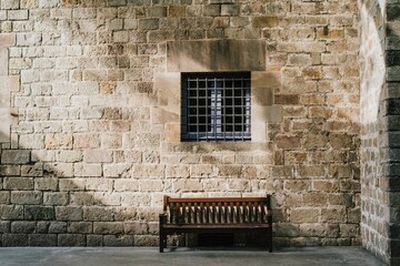 Wooden bench beneath historic stone wall with soft morning light
