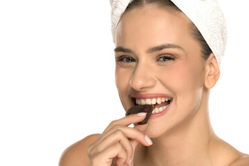 Happy woman smiling while biting chocolate dessert, studio shot on white background