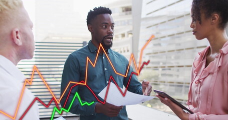 Three colleagues discussing chart overlays on terrace railing, with documents, tablet and laptop
