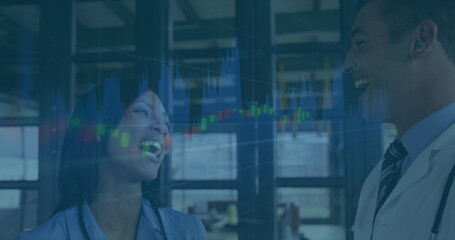 Laughing business professionals with stock market data image in office setting