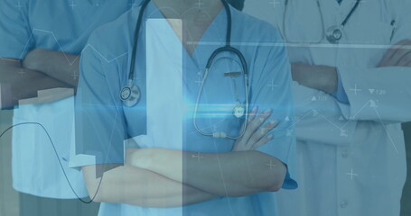 In hospital, healthcare professionals in scrubs reviewing image of medical data graphics