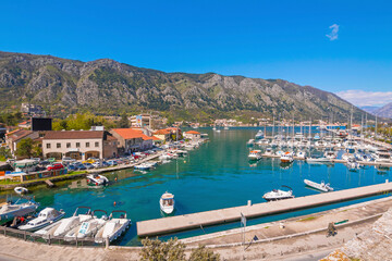 Kotor Bay shines under the sun as elegant yachts drift on crystal-clear waters, with the historic...