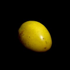 Artistic abstract shot of a whole maracuya set against a dark background. Brigth yellow exterior...