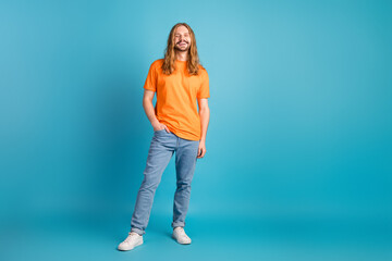 Portrait of a handsome young man wearing a vibrant orange t-shirt and jeans standing confidently...