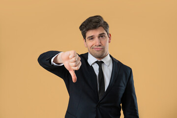 Businessman in suit giving thumbs down dislike with disapproving look on beige