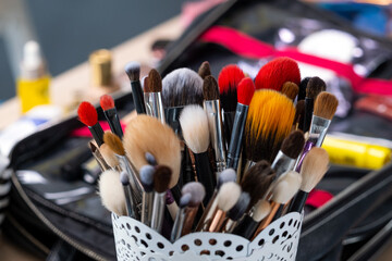 Collection of makeup brushes ready for facial beauty routine, stored neatly in decorative cup, open...