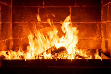 Wood logs burning in indoor fireplace, orange-yellow fire creating cozy warm feeling, rustic charm, countryside atmosphere, romantic winter night scene, peaceful comfort concept