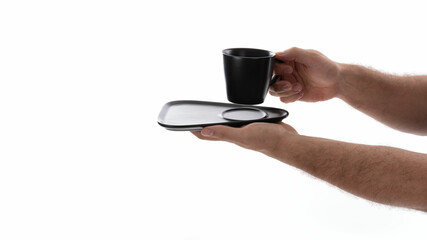 Hands holding a black cup on a tray