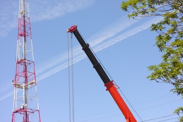 Construction crane boom against a blue sky with television tower on the background