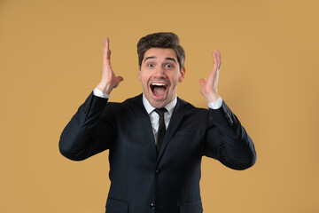Surprised businessman making mind blown gesture on warm beige background