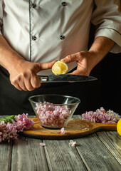 A skilled chef slices a lemon above a bowl filled with delicate acacia flowers while working in a...