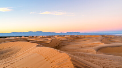 Naklejka premium A panoramic landscape photograph of sand dunes at sunset.