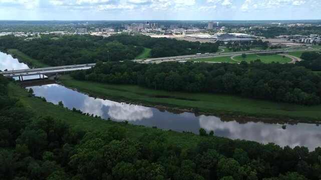 The Pearl River flowing through natural green space outside of Jackson, Mississippi with cars traveling on interstate highway 