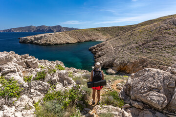 A woman with a backpack walks along the coast of the island of KRK, Konjska beach,