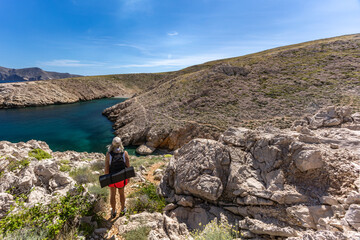 A woman with a backpack walks along the coast of the island of KRK, Konjska beach,