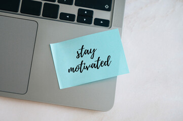 Stay motivated message on blue sticky note, laptop keyboard background, business and psychological...